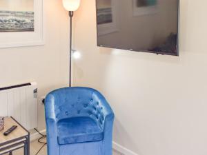 einen blauen Stuhl in einem Zimmer mit einem Tisch in der Unterkunft Rookmead Cottage in Yarmouth