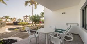 a white table and chairs on a patio with palm trees at ILUNION Costa Sal Lanzarote in Puerto del Carmen
