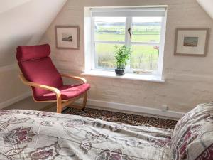 ein Schlafzimmer mit einem roten Stuhl und einem Fenster in der Unterkunft Rookmead Cottage in Yarmouth