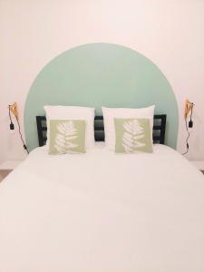 ein weißes Bett mit zwei Kissen darüber in der Unterkunft °Appart' 1 Audincourt centre ° in Audincourt