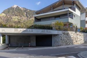 a building with a parking garage and a mountain at Mali Apartments Balcony in Tirolo