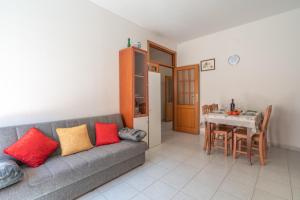 a living room with a gray couch with red and yellow pillows at AffittaSardegna - Casa Merisi in Alghero