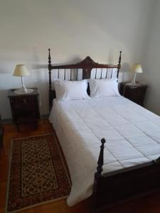 1 dormitorio con 1 cama grande con sábanas y almohadas blancas en Casa da Tia Lena, en Coímbra
