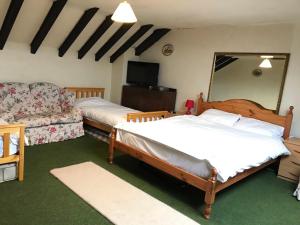 a bedroom with two beds and a couch and a mirror at Characteristic 6-Bed Cottage on Exmoor in Minehead