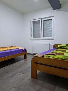 twee bedden in een kamer met twee ramen bij Apartman Knežević in Donja Varoš