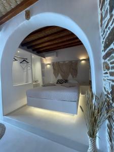 ein weißes Schlafzimmer mit einem Bett in einem Torbogen in der Unterkunft Psathi in Kythnos + 13 Fotos