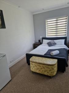 um quarto com uma cama com um repousa-pés e uma janela em Spacious Luxurious Serviced Accomodation em Doncaster