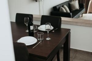 uma mesa de madeira com copos e garrafas de vinho em Ovis Hotel Apartments em Agia Napa