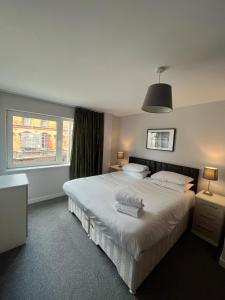 a bedroom with a large white bed and a window at Quayside Apartments in Cardiff