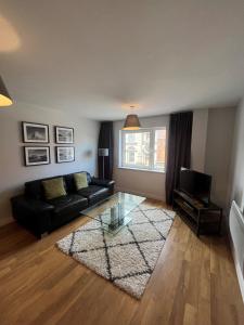 a living room with a black couch and a glass table at Quayside Apartments in Cardiff