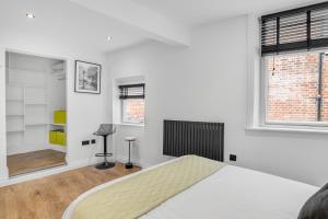 een witte slaapkamer met een bed en 2 ramen bij Nadler Studios in Norwich