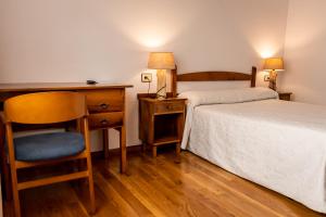 a bedroom with two beds and a desk and a chair at Hostal Restaurante Ventasierra in Valdoré