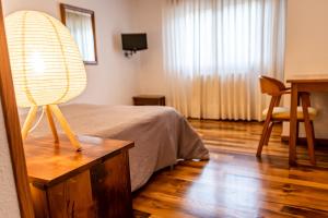 1 dormitorio con 1 cama y 1 mesa con lámpara en Hostal Restaurante Ventasierra, en Valdoré