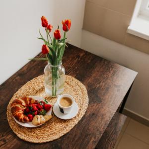 una mesa con un plato de comida y flores y una taza de café en SPACIOUS COZY APARTMENT ORADEA, en Oradea