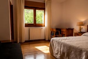 a bedroom with a bed and a window and a desk at Hostal Restaurante Ventasierra in Valdoré