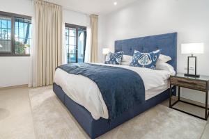 a bedroom with a large bed with a blue headboard at AB26- Lovely Holiday Home in Aldea Blanca in Marbella +32 photos