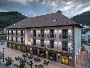 un grand bâtiment avec des tables et des chaises devant lui dans l'établissement Silken Puerta de Irati, à Ochagavía