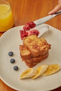 a plate of food with toast and fruit and a glass of orange juice at Epic Boutique Hotel in Medellín