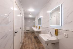 een witte badkamer met 2 wastafels en een spiegel bij Hotel Leeuwerik in Bad-Nieuweschans