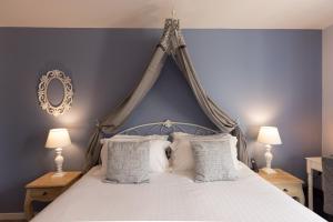 ein Schlafzimmer mit einem Himmelbett und weißen Kissen in der Unterkunft Hotel-Restaurant des Augustins - Cosy Places by CC - Proche Sarlat in Saint-Cyprien