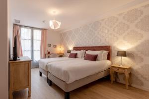 a bedroom with a large white bed and a window at Hôtel-Restaurant des Augustins in Saint-Cyprien