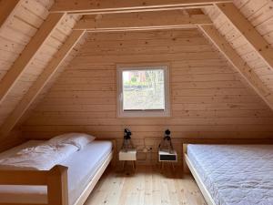 2 Betten in einem Holzzimmer mit Fenster in der Unterkunft Duża Woda in Dąbrówno