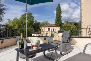 eine Terrasse mit einem Tisch, Stühlen und einem Sonnenschirm in der Unterkunft Hotel-Restaurant des Augustins - Cosy Places by CC - Proche Sarlat in Saint-Cyprien