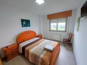 a bedroom with a bed and a chair and a window at Casa Dabuela Costa da Morte in Muxia