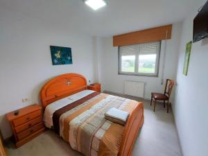 a bedroom with a bed and a chair and a window at Casa Dabuela INCostadaMorte in Muxia