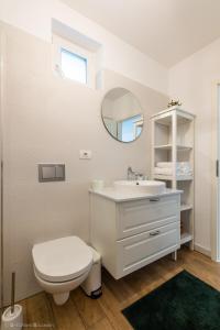 a white bathroom with a toilet and a sink at Red Fountain Studio in Braşov