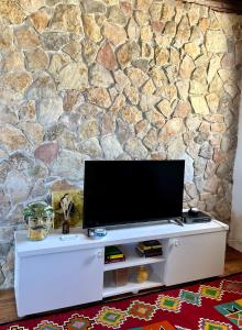 un televisore su un centro di intrattenimento bianco di fronte a un muro di pietra di Casale Toia a Scopello