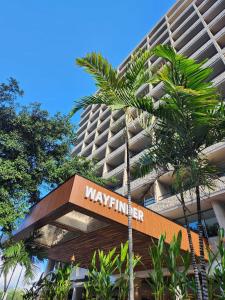a building with a sign in front of a palm tree at Wayfinder Waikiki in Honolulu
