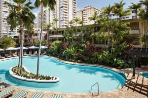 an empty swimming pool with palm trees and buildings at Wayfinder Waikiki - Voted Top 10 Best Hotels in Hawaii! in Honolulu