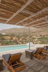 eine Terrasse mit 2 Liegestühlen und einem Pool in der Unterkunft ELIA Boutique Villas in Agia Galini