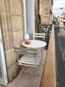 d'une table et de chaises blanches sur un balcon. dans l'établissement Appartement gare Saint jean, à Bordeaux