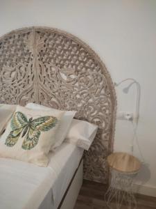 a bed with a wooden headboard with a butterfly pillow at VFT Puerta de Córdoba in Baeza