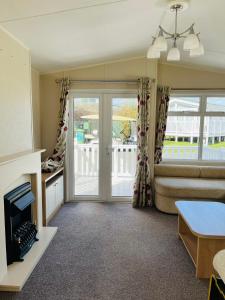 ein Wohnzimmer mit einem Sofa und einer Glasschiebetür in der Unterkunft Roslyn at Lower Hyde Park, Isle of Wight in Shanklin