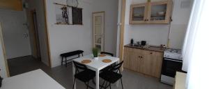 una pequeña cocina con mesa blanca y sillas en Blue Moon Apartman, en Eger