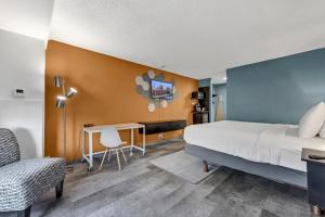 a bedroom with a bed and a desk with a tv at Buffalo Airport Hotel in Cheektowaga