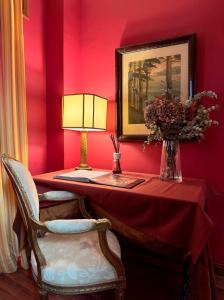 une chambre rouge avec une table, une lampe et une chaise dans l'établissement Almunia de San Miguel, à Tolède