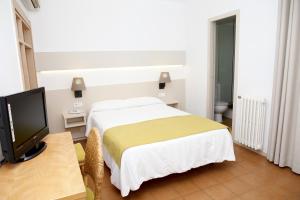 a bedroom with a bed and a desk with a television at Hotel Ubaldo in Cadaqués