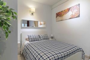 um pequeno quarto com uma cama com um cobertor xadrez em Apartamento céntrico y confortable em Madri