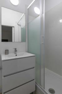 een witte badkamer met een wastafel en een douche bij Apartamento céntrico y confortable in Madrid
