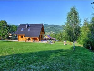 a log cabin with a large green field in front of it at Miodowa Chata in Brenna