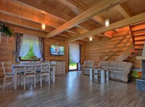 een woonkamer met een tafel en stoelen en een televisie bij Miodowa Chata in Brenna