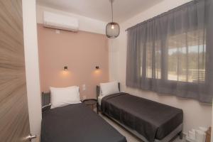 two beds in a small room with a window at ELIA Boutique Villas in Agia Galini