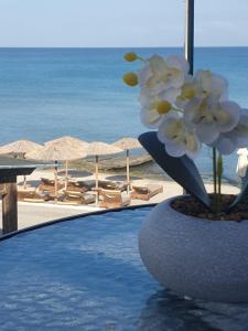 un vaso con fiori di fronte a una spiaggia di Sandy feet comfort suite a Kardámaina