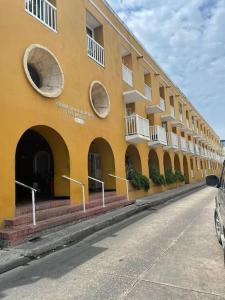 ein gelbes Gebäude mit Bögen an der Seite einer Straße in der Unterkunft Cómodo apto zona histórica Cgena in Cartagena de Indias