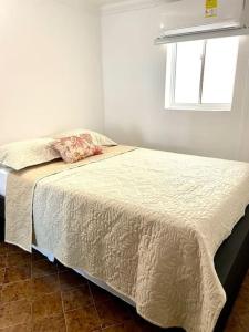 Bett in einem weißen Zimmer mit Fenster in der Unterkunft Cómodo apto zona histórica Cgena in Cartagena de Indias