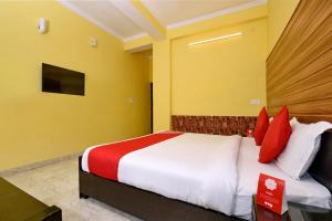 a bedroom with a bed with red and white pillows at OYO Flagship Maira Residency in Dehradun
